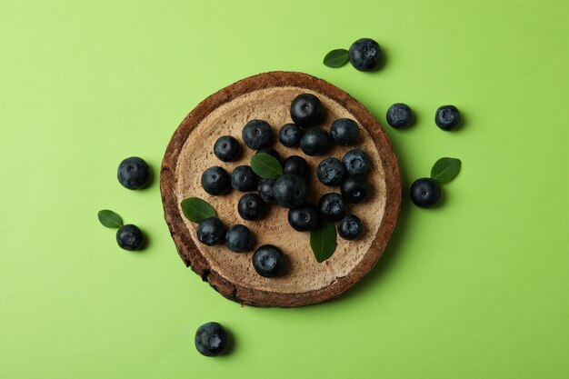 Fresh blueberry with leaves on green surface