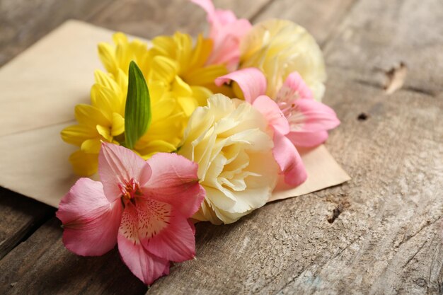 木製の背景の封筒に花の新鮮な花束