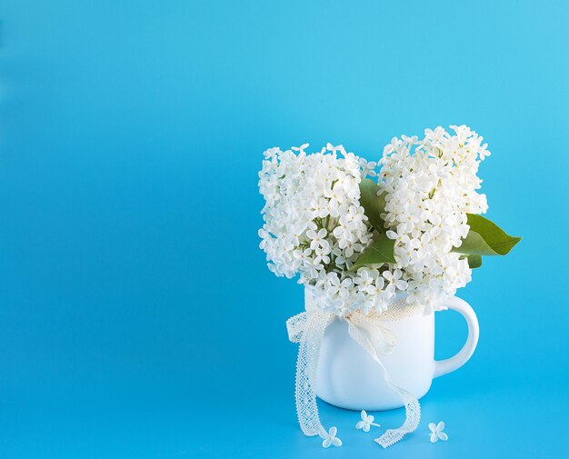 Fresh bouquet of white lilac in a circle on blue background Minimalist home decor copyspase