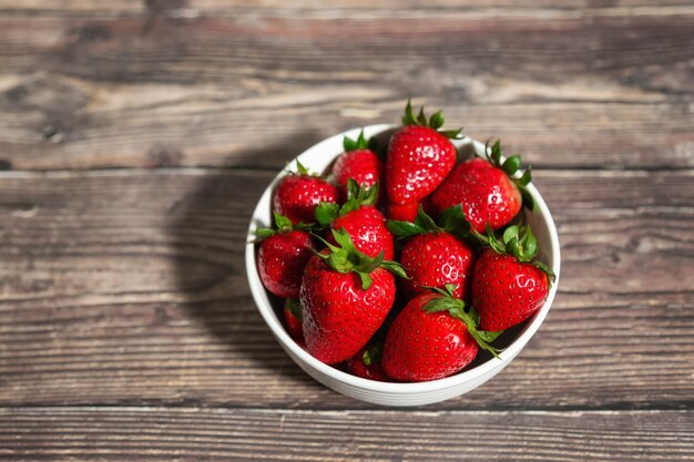 Fresh bowl of strawberries on a wooden table