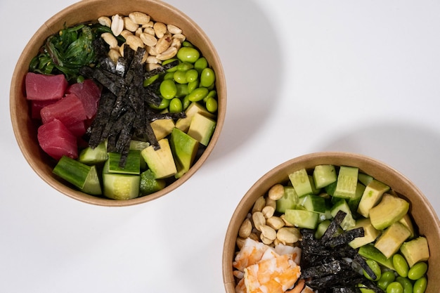 Fresh bowls with shrimps tuna green beans rice peanuts and seaweed on the white background