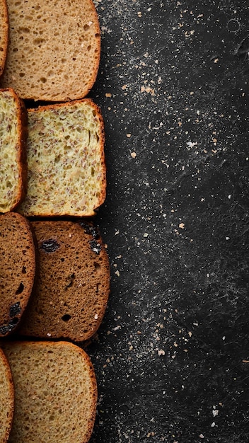 Fresh bread Assortment of sliced black and white bread Top view Black stone background rustic style