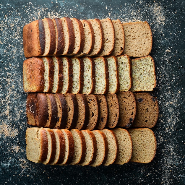 Fresh bread Assortment of sliced black and white bread Top view Black stone background rustic style