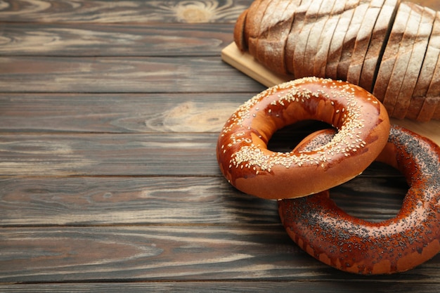 Photo fresh bread bagel and bread with poppy seed on brown wooden background