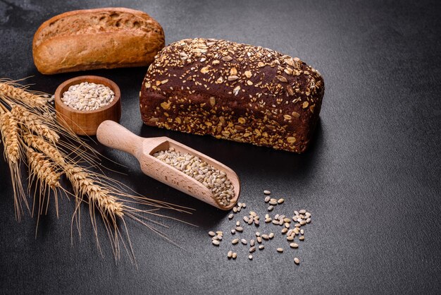 Fresh Bread on black background, top view, copy space. Homemade fresh baked various loafs of wheat and rye bread