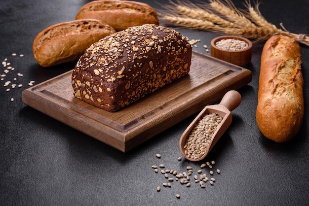 Fresh Bread on black background, top view, copy space. Homemade fresh baked various loafs of wheat and rye bread