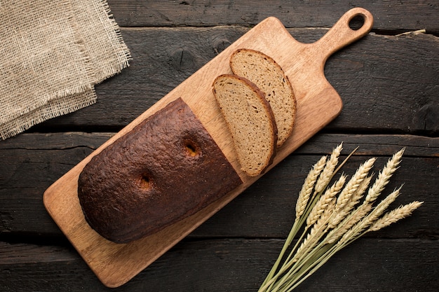 Fresh bread on a board with wheat on wood