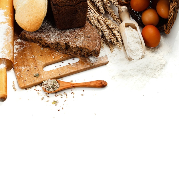 Fresh bread on cutting Board, scoop with flower and seeds isolated over white