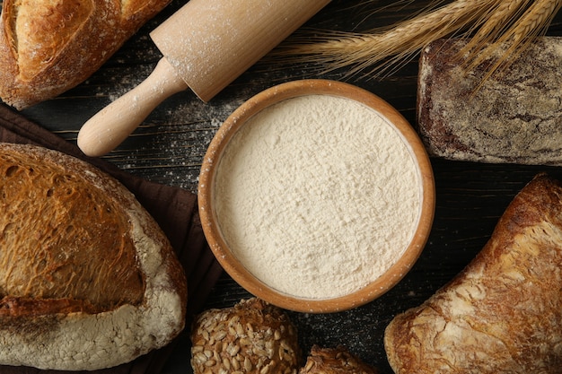 Fresh bread, flour, spikelets and rolling pin on wooden