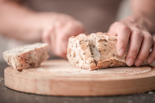 Pane fresco in primo piano delle mani sulla vecchia tavola di legno