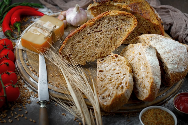 Свежий хлеб на старой предпосылке с аксессуарами кухни на таблице.