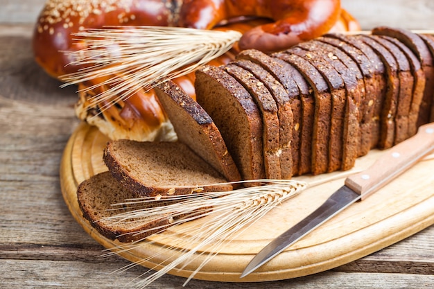 Свежий хлеб на старой предпосылке с аксессуарами кухни на таблице.