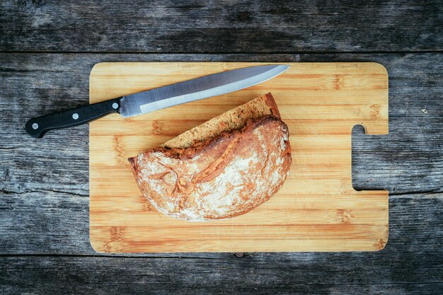 Photo fresh bread in slices on wooden cutting board outdoors