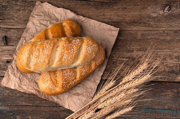 Fresh bread spikelets of wheat on a brown wooden background.