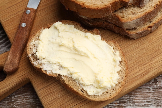 Fresh bread with butter and knife on wooden table above view