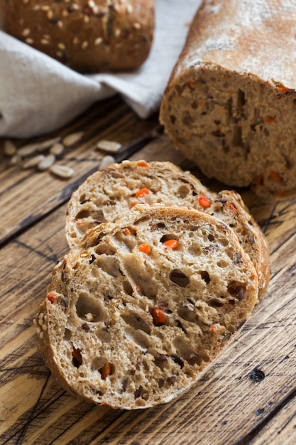 Fresh bread with sunflower seeds, sesame seeds and flax are cut into pieces on a cutting board.