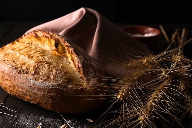 Fresh bread with wheat on wooden table