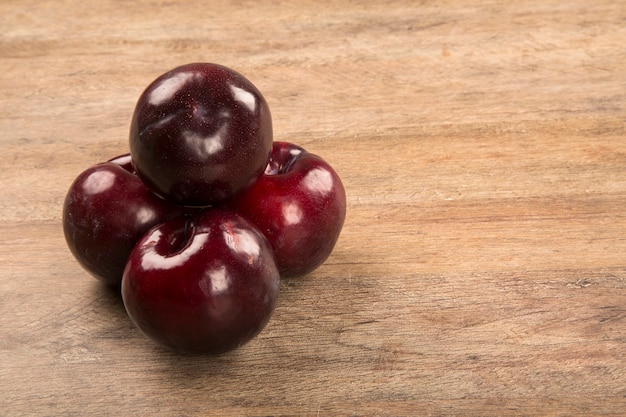 Fresh bright plums in the bowl on board. Fresh fruits.