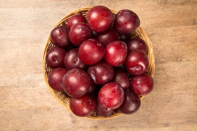 Fresh bright plums in the bowl on board. Fresh fruits.