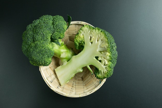 Fresh broccoli in basket on black background 