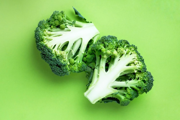 Fresh broccoli on a green background cut in half Closeup minimal style food concept freshness