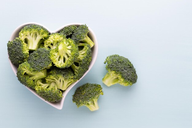 Fresh broccoli in a heart shaped bowl on a wooden background.