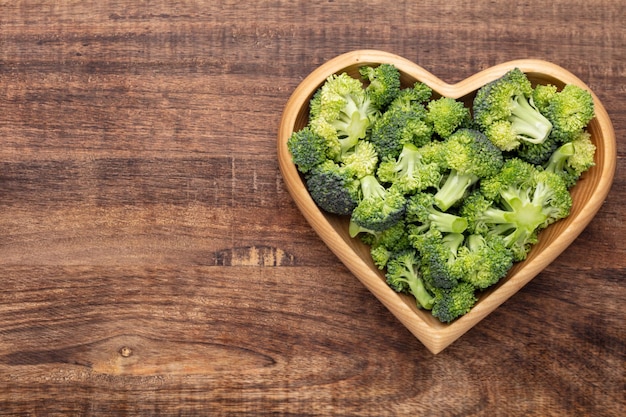 Fresh broccoli in a heart shaped bowl on a wooden background