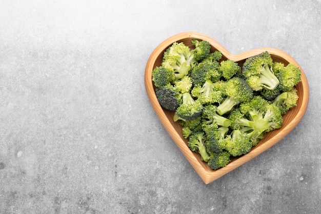 Fresh broccoli in a heart shaped bowl on a wooden background