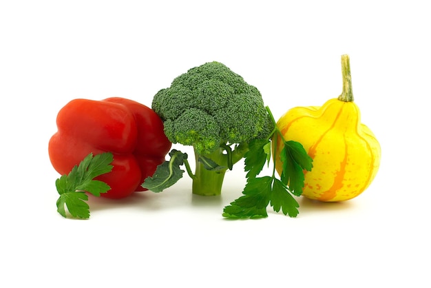 Fresh broccoli red bell peppers squash and sprig of parsley on white background