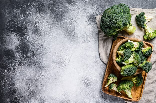 Fresh broccoli in a wooden bowl. Gray wall. Top view. Space for text