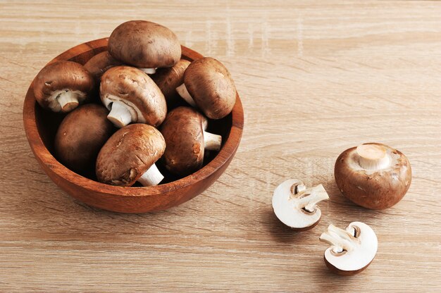 Fresh brown chestnut mushrooms whole in wooden plate