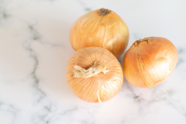 Fresh bulbs of onion on marble table