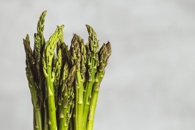 Fresh bunch of asparagus with smooth daylight on grey stone background/top view and free space for text