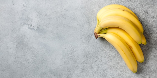 Mazzo fresco di frutti di banana sulla superficie di pietra