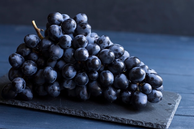 A fresh bunch of blue grapes, on a blue table