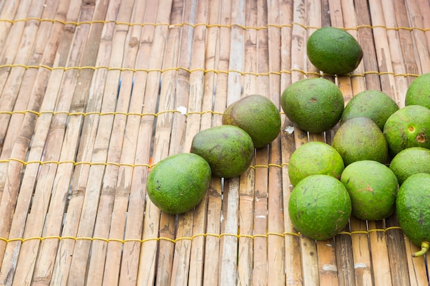 Свежий кучу зеленых авокадо на фоне деревянной сетки