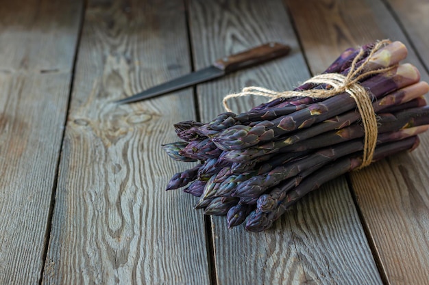 Foto mazzo fresco di asparagi viola su sfondo di legno scuro concetto di cibo sano