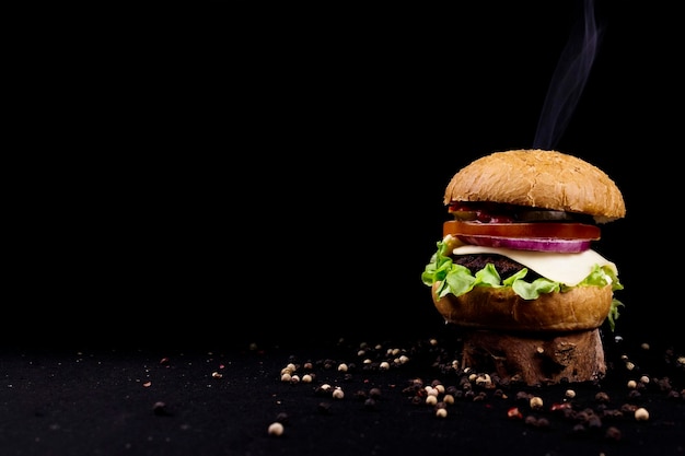 Foto hamburger fresco su sfondo nero nel fumo