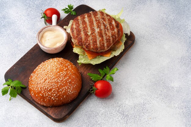 Fresh burger served on wooden board on gray surface