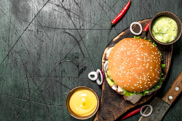 Fresh burger with beef, bacon and fresh vegetables. On a rustic background.