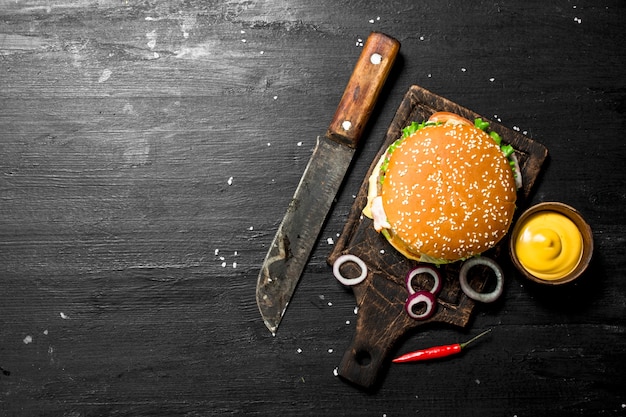 Photo fresh burger with beef, bacon and vegetables. on the black chalkboard.