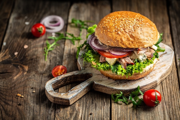 Fresh burger with blue cheese and arugula on wooden surface