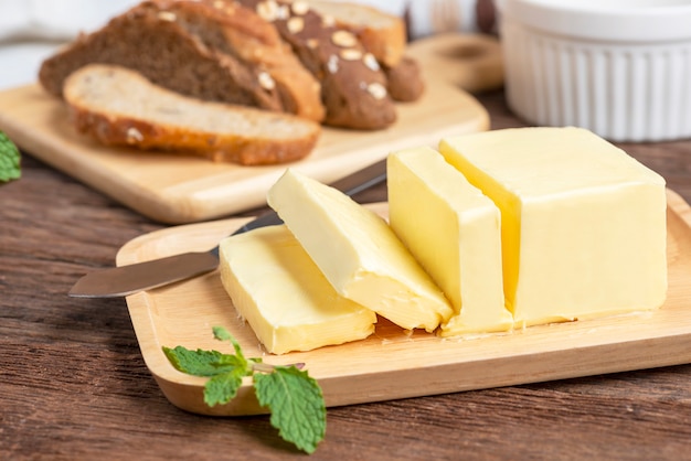 新鮮なバターは、木製のプレートとパンにナイフでカット。