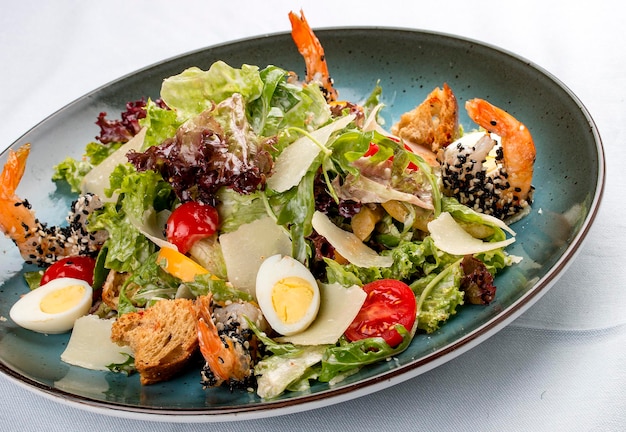 Fresh caesar salad on white bowl with parmesan cheese and shrimps In a decorative plate