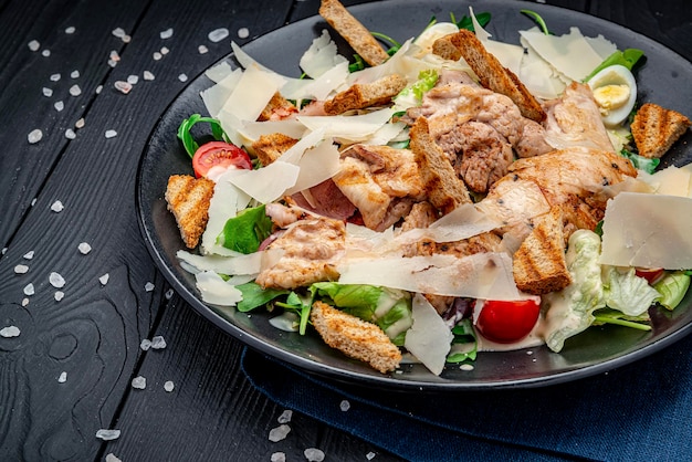 Fresh caesar salad in white plate on dark wooden table Top view