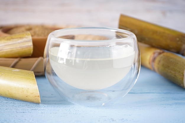 Fresh cane juice and sugarcane on a wooden background closeup