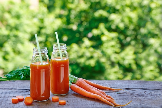 Fresh carrot juice in glass bottles on the table