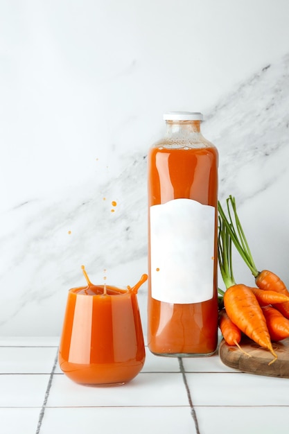 Fresh carrot juice in glass on table and light background with fresh carrot on wooden deck. splash of carrot juice