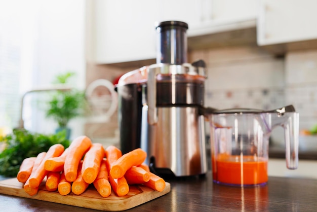 Fresh carrot juice preparation with juicer at home