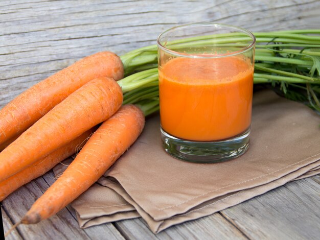 Fresh carrot juice on a wooden table close up